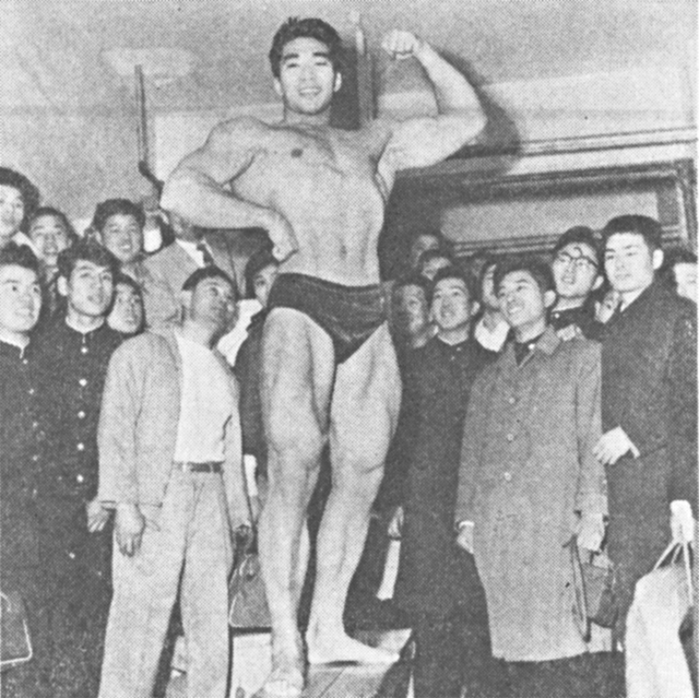 オリンピック重量挙二連勝、ボディビル界でも数々のタイトルを獲得したトイー・コーノ。写真は1958年”里帰り”したとき集まった日本のファンの前でポーズをとるコーノ。